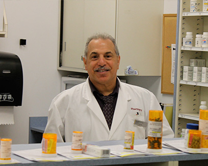 Pharmacist standing in pharmacy with prescription bottles